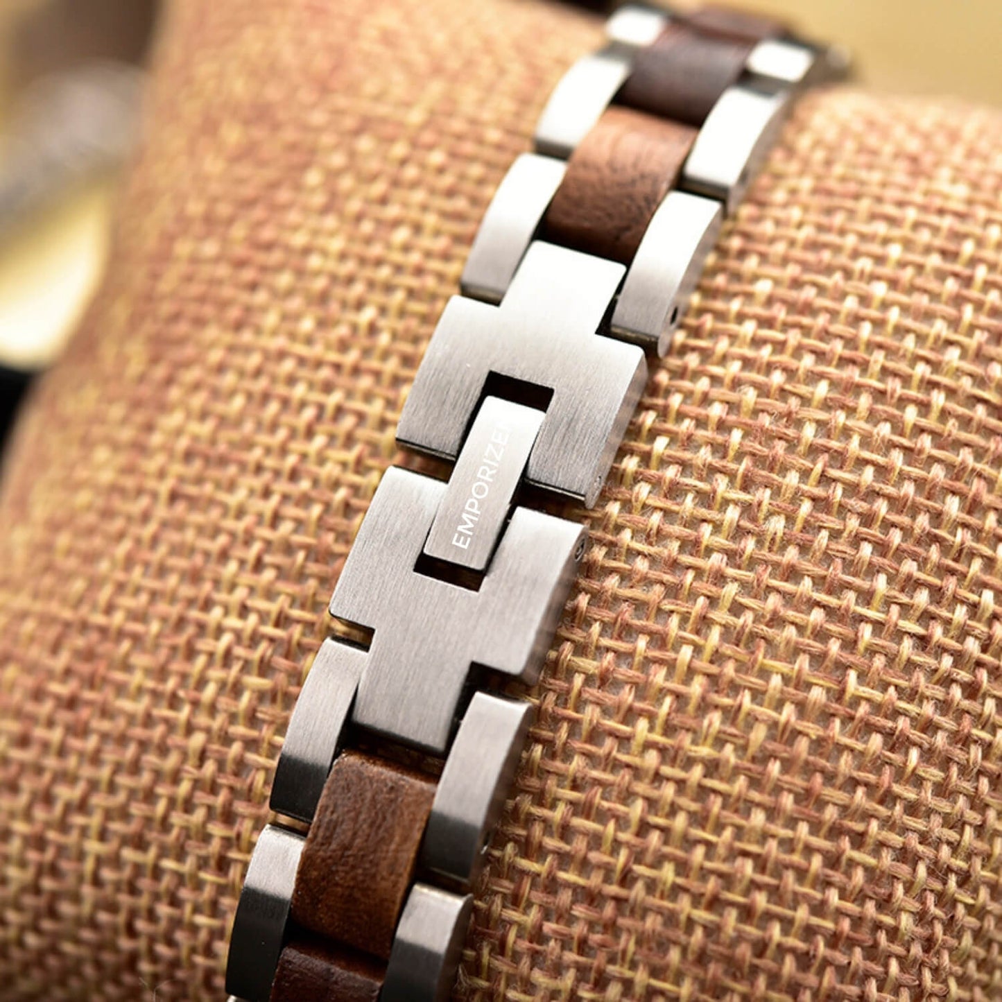 Close-up of a steel and wood bracelet on a textured surface